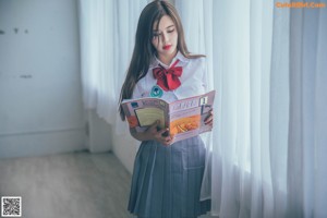 A woman in a school uniform standing in front of a blackboard.