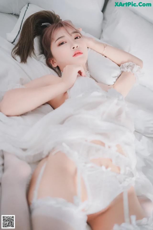 A woman laying on a bed in a white lingerie.