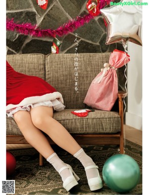 A woman in a santa hat holding a pink bag.