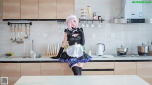 A woman in a maid outfit sitting on a table next to a plant.