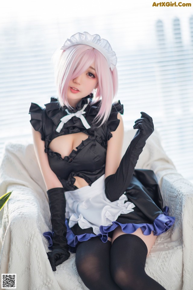 A woman in a maid outfit sitting on a white chair.