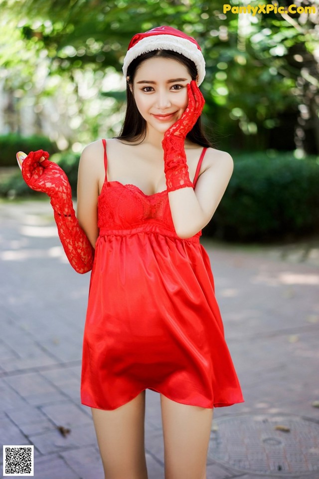 A woman in a red dress and a santa hat posing for a picture.
