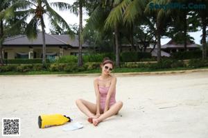 A woman in a black bikini standing next to a pool.