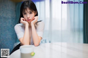 A woman sitting on top of a table in a room.