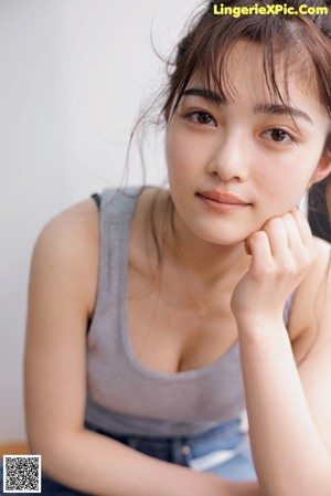 A woman sitting on top of a couch next to a window.