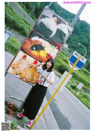 A woman in a yellow shirt and white skirt posing for a picture.