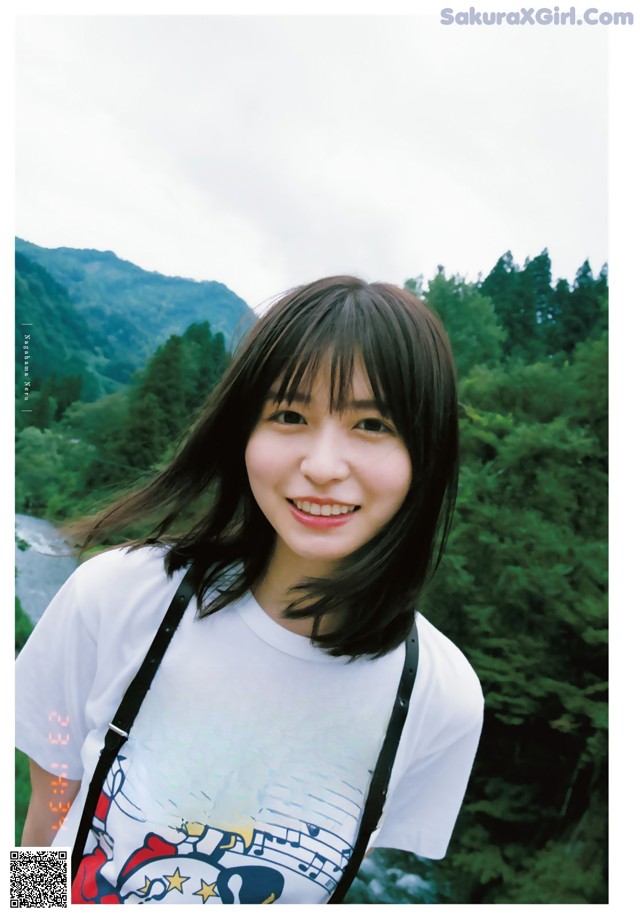 A young woman wearing a white shirt with a CDG logo on it.