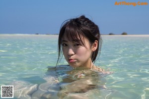 A woman in a bikini standing under a shower.