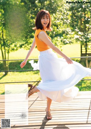 A woman in a yellow dress standing in front of a window.