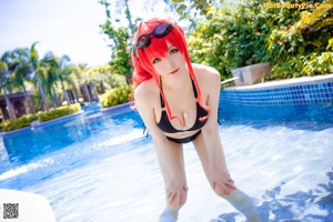A woman in a black bikini sitting on the edge of a pool.