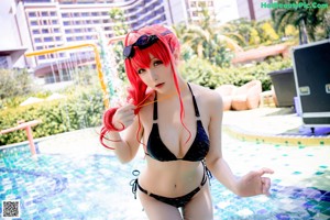 A woman in a bikini sitting by a swimming pool.