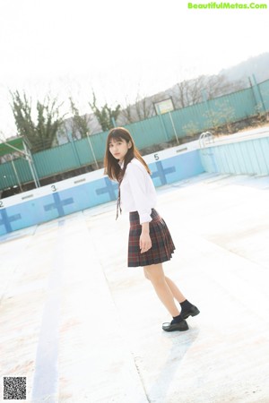 A woman in a pink shirt and plaid skirt posing for the camera.
