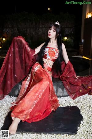 A woman in a red dress standing in a pool.