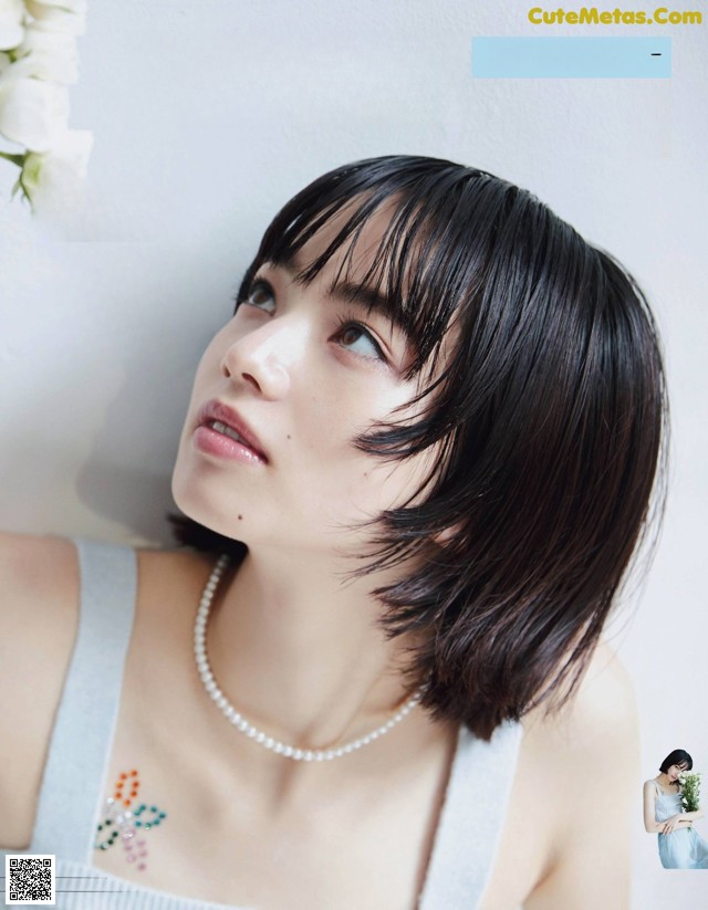 A woman with short black hair wearing a white dress.