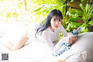 A woman sitting on a white couch on a wooden deck.