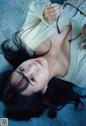 A woman in a white bra and blue shirt laying on a couch.