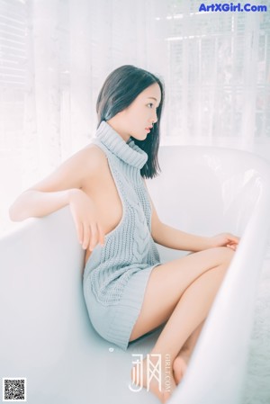 A woman in a blue dress sitting on a white rug.