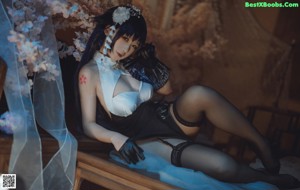 A woman in lingerie sitting on a bed next to a window.