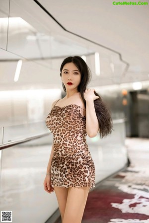 A woman in a leopard print dress posing in front of a mirror.