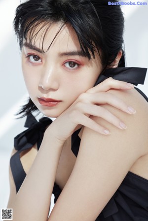 A woman with long black hair holding a gold eyeliner.