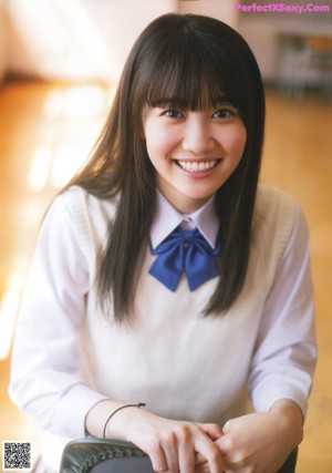 A girl in a school uniform holding a chalkboard in front of her.