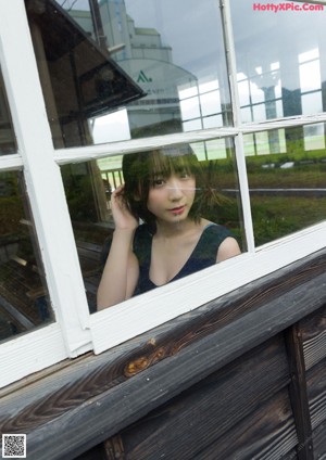 A woman in a black dress standing in front of a window.