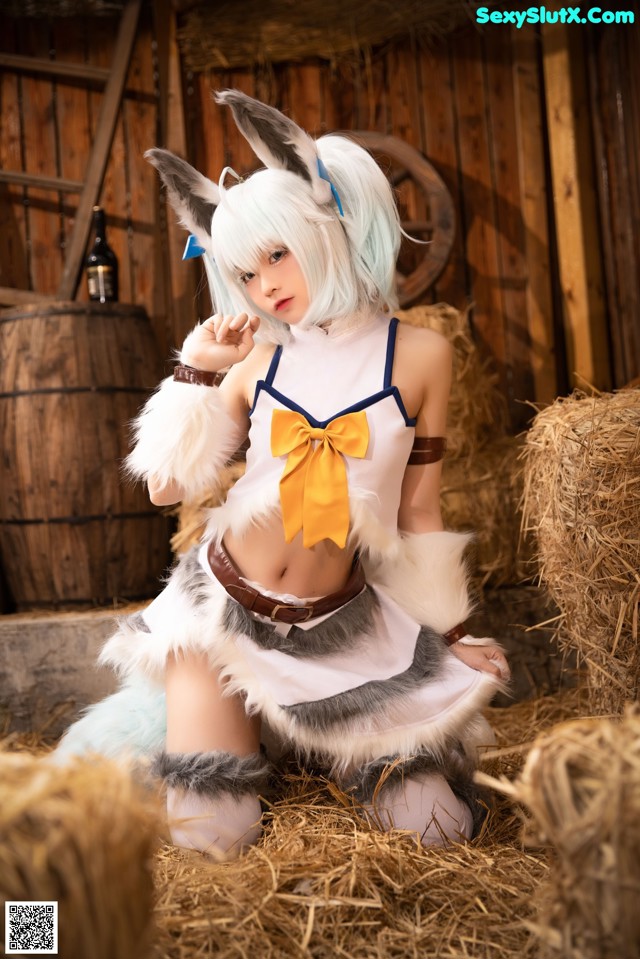 A woman in a bunny costume sitting on a pile of hay.