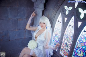 A woman in a wedding dress sitting in front of a window.