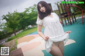 A woman in a white shirt is posing for the camera.