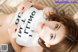 A woman in a white lingerie sitting on a bed.