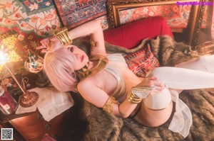 A woman with pink hair sitting on a rug in a room.