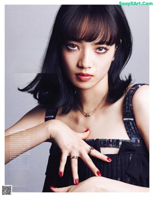 A woman with long black hair wearing a necklace and a ring.