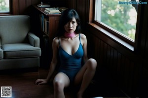 A woman in a pink dress sitting on a bed.