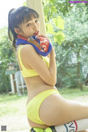 A woman in a pink shirt and yellow shorts kicking a soccer ball.