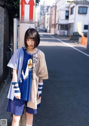 A woman in a blue top and plaid skirt posing for a picture.