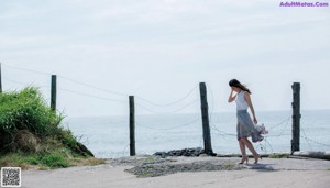 A woman in a white shirt and a skirt on the beach.
